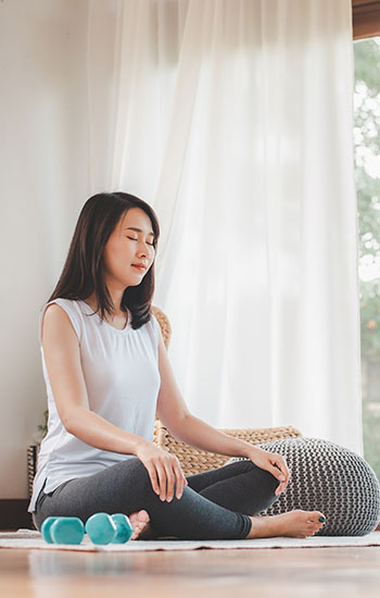 Woman doing a meditation in a cross legged seating position on the floor
